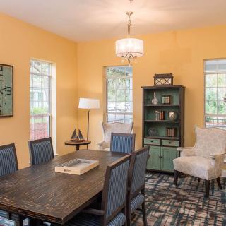 A cozy dining room with yellow walls and a dark wood table, complemented by elegant chairs and a stylish bookshelf.