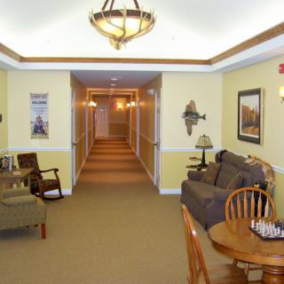 A cozy lounge area with furniture leading to a well-lit hallway.