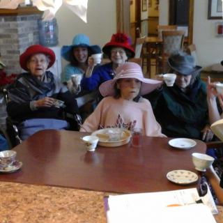 A group of elderly individuals enjoying a tea party, wearing colorful hats.