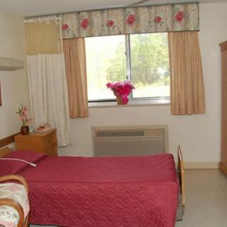 A cozy bedroom with a single bed, dresser, and a window adorned with curtains.