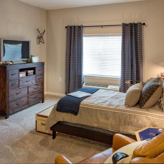 A cozy and well-furnished bedroom with a bed, dresser, and window.