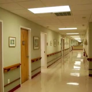 A long, empty hospital hallway with doors on both sides.