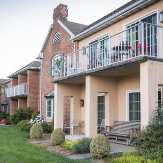 A row of residential apartments featuring balconies and a well-maintained lawn.