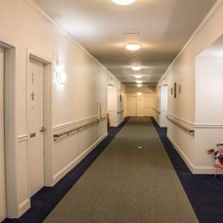 A well-lit hallway with carpeted floors and handrails on the walls.