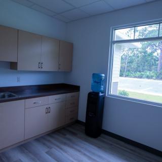 Office kitchen area with cabinets, a water cooler, and a window.