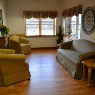 A cozy living room with a sofa, armchairs, and large windows.