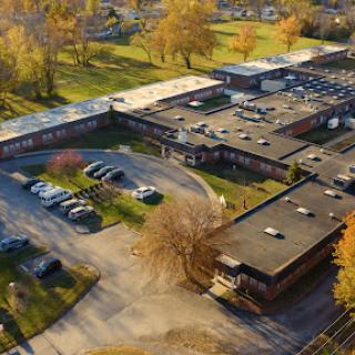 Aerial view of a modern building surrounded by greenery and autumn trees.