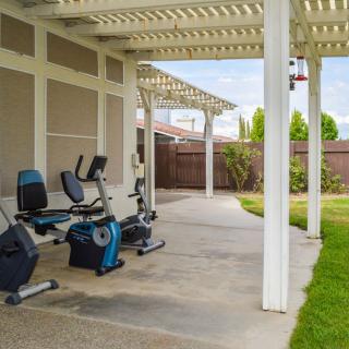 Outdoor home gym setup with exercise bikes under a covered patio.