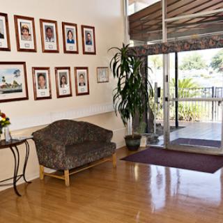 A welcoming lobby with a cozy seating area, adorned with framed photographs and a vibrant plant.