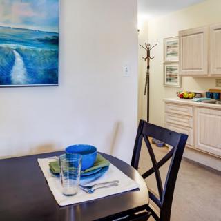 A cozy dining area with a neatly set table and visible kitchen in the background.