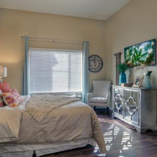 A cozy bedroom with a neatly made bed, stylish decor, and natural light streaming in through the window.