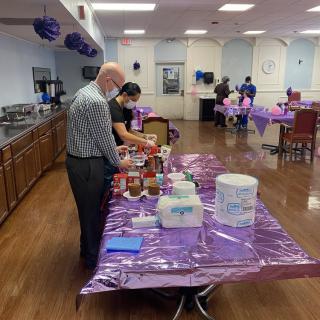 An indoor gathering with a purple-themed setup and a table of food.