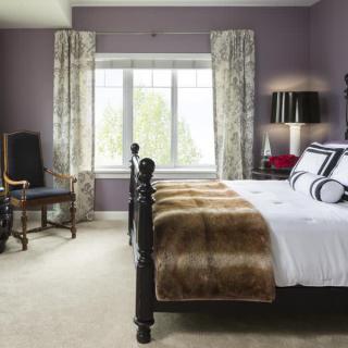 A stylish and cozy bedroom featuring a large bed, decorative pillows, and elegant curtains framing a window.