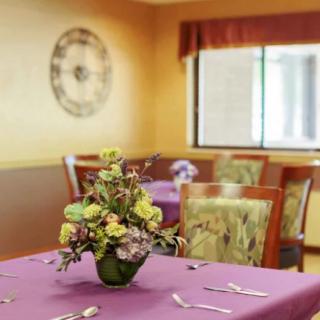 A warmly decorated dining room featuring tables with floral centerpieces.