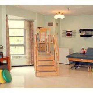 A therapy room equipped with exercise stairs, mats, and other rehabilitation tools.
