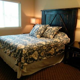A cozy bedroom with a neatly made bed and patterned bedding, illuminated by table lamps.
