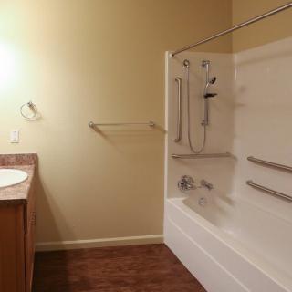 A clean and simple bathroom with a bathtub, sink, and towel rack.