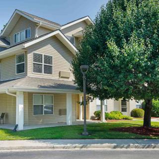 A suburban residential house with a well-maintained exterior and a large tree in the front yard.