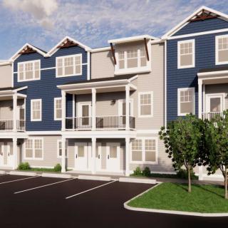 A row of modern three-story townhouses with blue and gray siding and a parking lot in front.