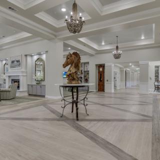 A luxurious and spacious living room with elegant chandeliers and a central art sculpture.