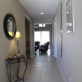 A modern hallway with neutral tones, featuring a mirror, decorative table, and a lamp.