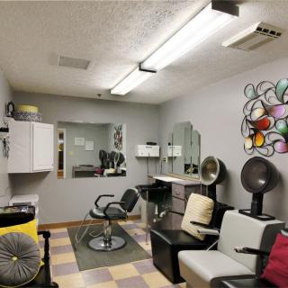 A cozy hair salon interior with chairs, mirrors, and vibrant artwork on the wall.