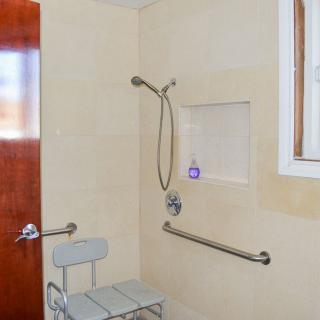An accessible bathroom with a shower featuring grab bars and a shower chair.
