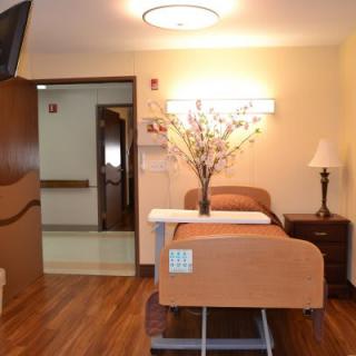 A clean and well-decorated hospital room with a bed and floral arrangement.