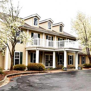 A large two-story house surrounded by blooming trees.
