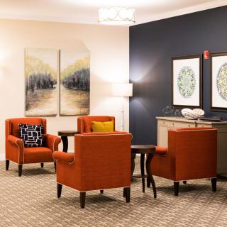 A cozy living room with orange chairs, artwork on the walls, and a warm atmosphere.