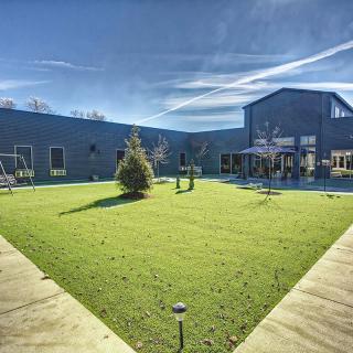 A spacious courtyard with green grass and a building in the background under a clear blue sky.