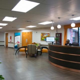 A modern reception area with a curved desk, comfortable seating, and bright lighting.