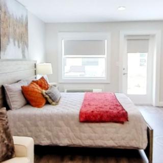 A modern bedroom with contemporary decor, featuring a large bed adorned with stylish pillows and a vivid red blanket.