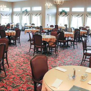 An elegant and formal dining room with neatly arranged tables and chairs, featuring a patterned carpet.