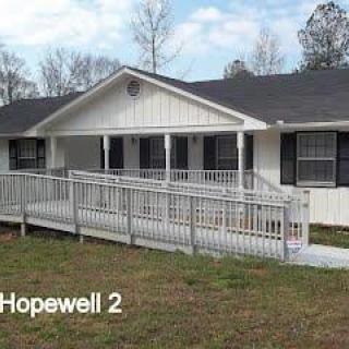 A single-story white house with a front porch and an accessibility ramp.
