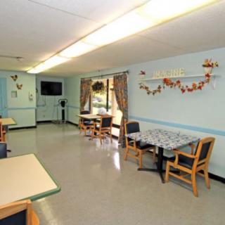 A cozy dining area with tables and chairs, decorated with wall hangings and curtains.