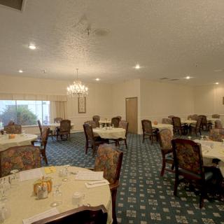 A spacious dining room with elegantly set tables and classic wooden chairs.