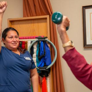 A healthcare professional guides a client through an exercise session with weights, promoting fitness and rehabilitation.