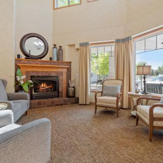 A cozy living room with a fireplace, ample seating, and large windows overlooking the outdoors.