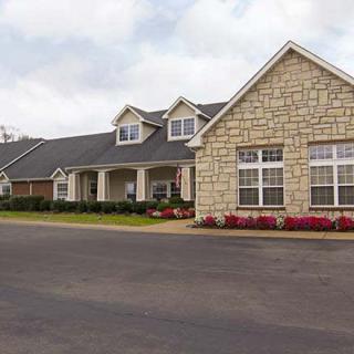 A suburban house with a stone facade and neatly landscaped surroundings.