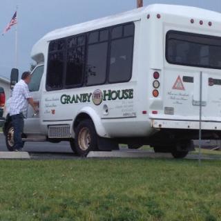 A person approaches a community transport bus labeled 'Granny House'.