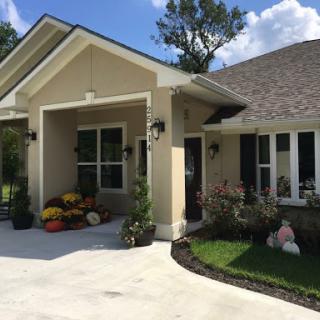 A beautifully landscaped home with a welcoming front porch and colorful autumn decorations.