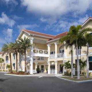 A two-story tropical building with palm trees under a cloudy sky.