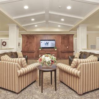 A cozy living room with striped chairs and a central coffee table facing a wall-mounted television.