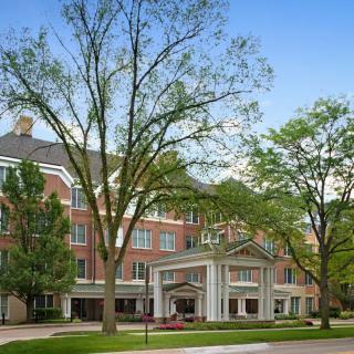 A beautiful brick building surrounded by lush trees on a college campus.