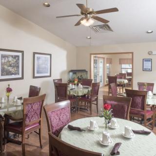 A cozy dining room setup with tables and chairs, featuring elegant decor and a ceiling fan.