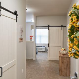 A hallway with sliding barn doors and a decorative sunflower wreath.