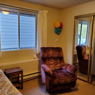 A cozy bedroom corner with a recliner, nightstand, and mirrored closet doors.