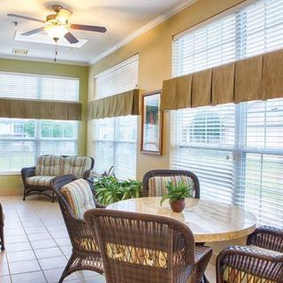 A cozy living room with rattan furniture and ample natural light streaming through large windows.