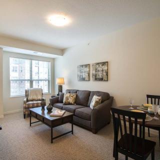 A cozy living room with a sofa, armchair, coffee table, and dining area.
